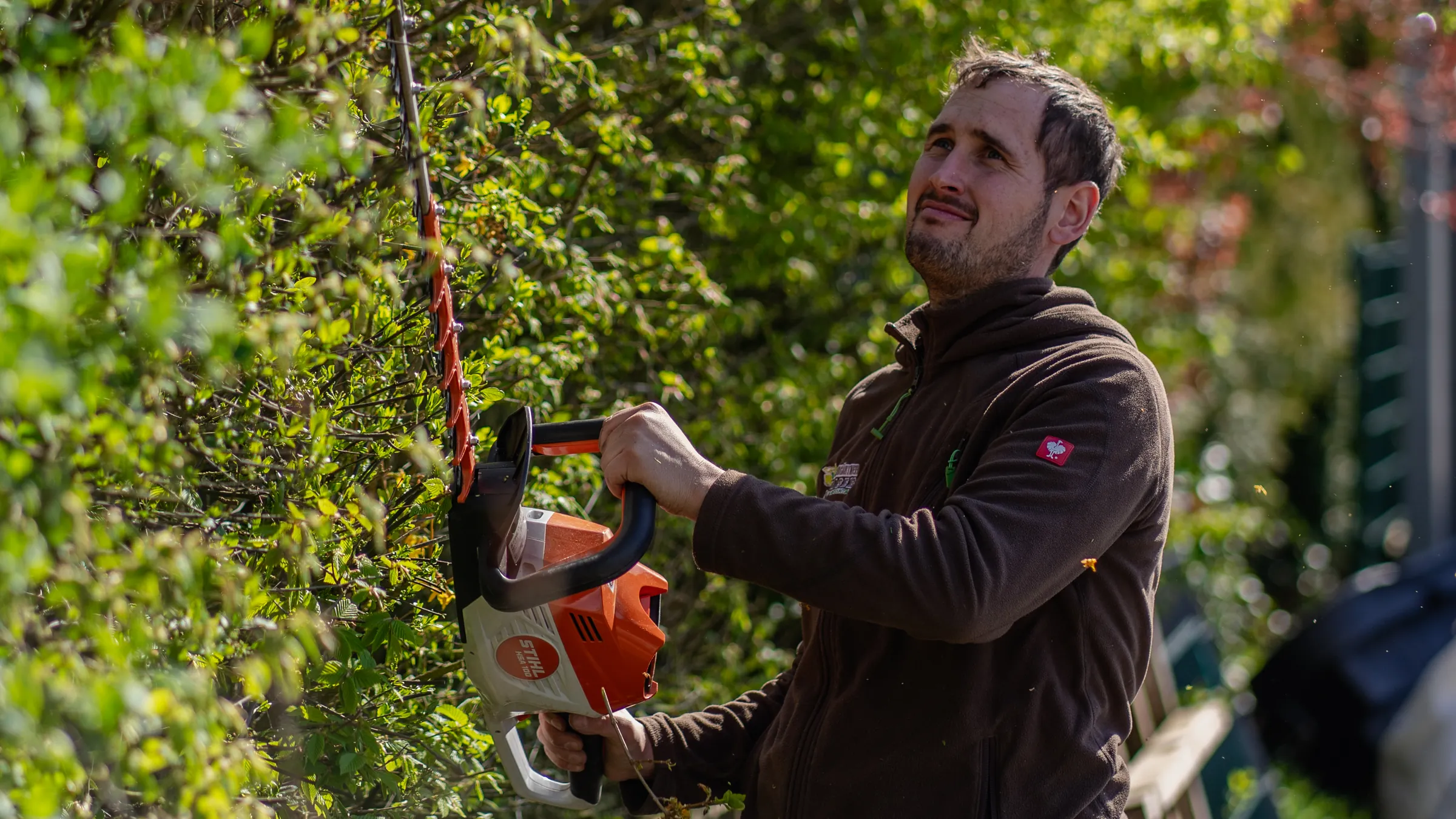 Mitarbeiter von Meistergärtner Meiser schneidet mit der Heckenschere eine Hecke zurück