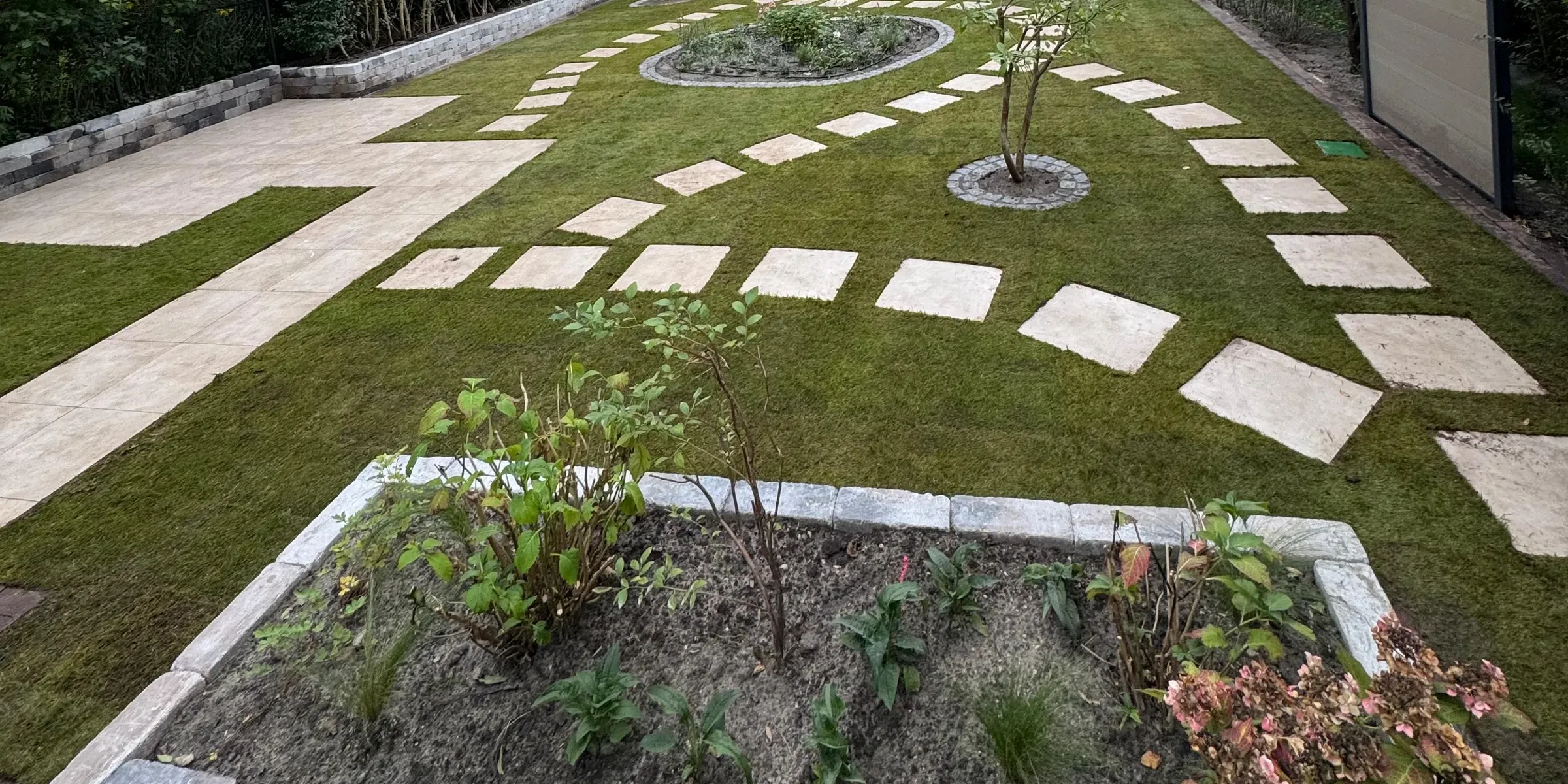 Derselbe Garten bei der Übergabe: Rasen, Trittplatten und das fertige Rondell